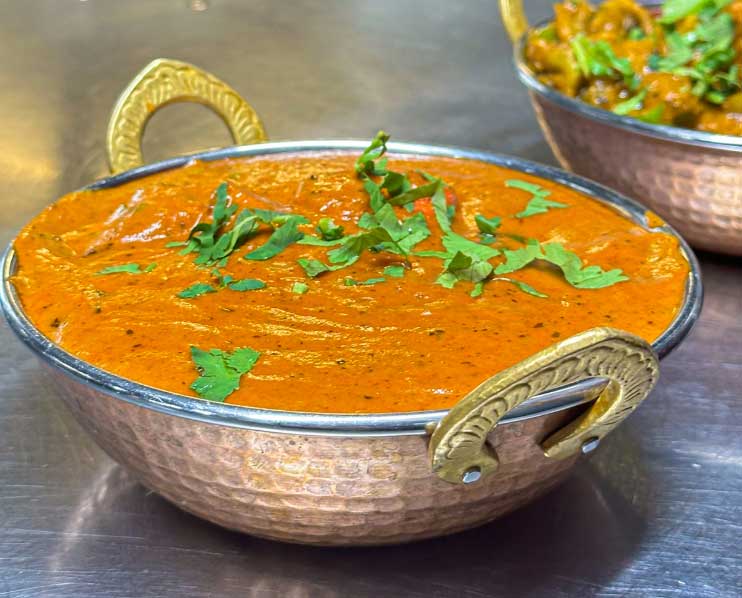 Vibrant Indian curry in a copper karahi, garnished with fresh cilantro.